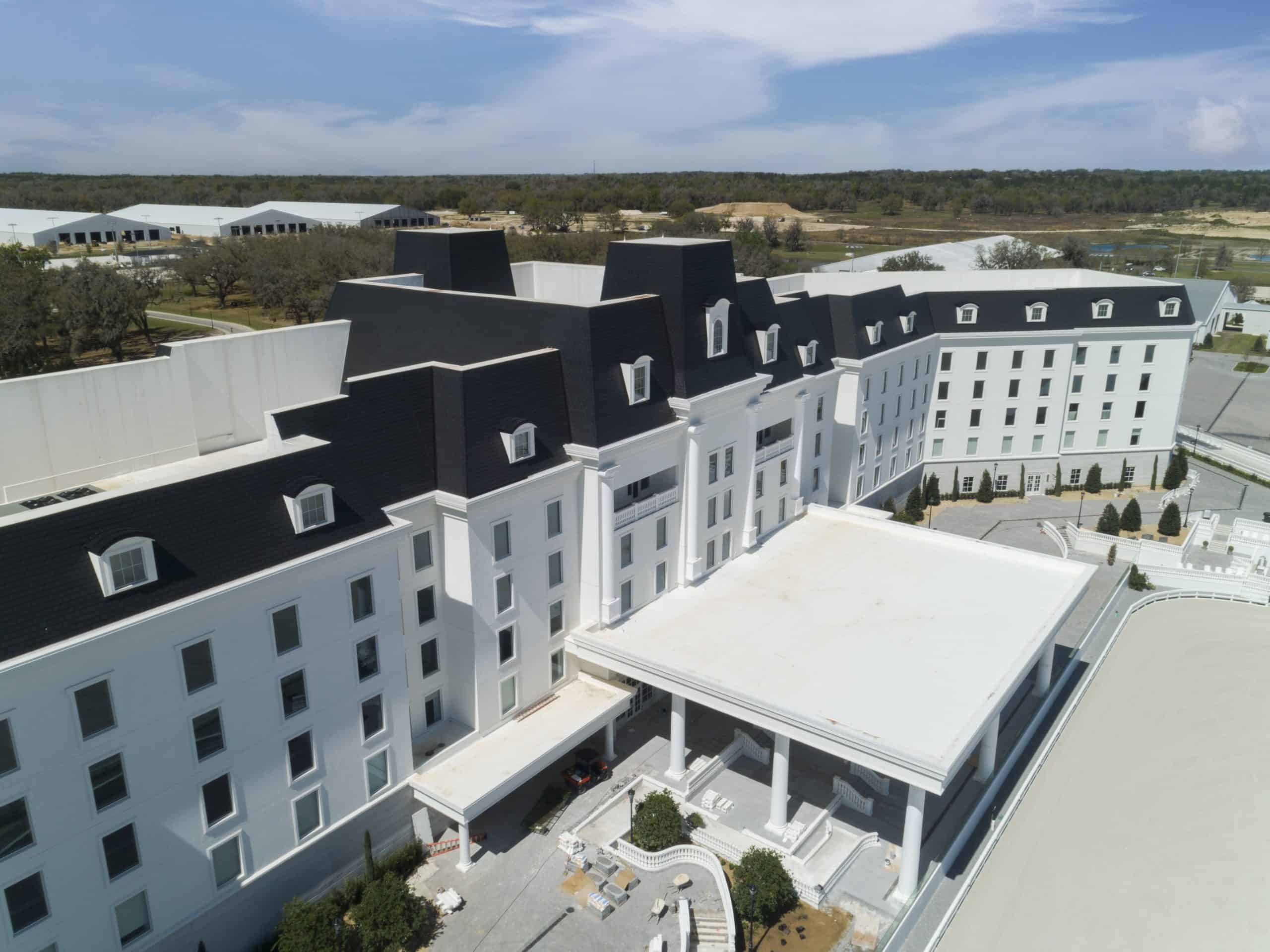 Equestrian hotel with white siding and an Onyx Black Enviroslate composite slate roof with some of the equestrian grounds visible