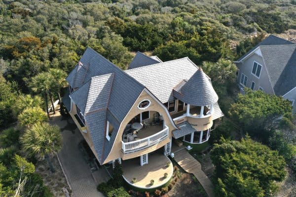 Aerial view of the roof of a home on Bald Head Island with trees in the background. The roof has Enviroshake Silvered Cedar composite roof tiles and copper flashing.