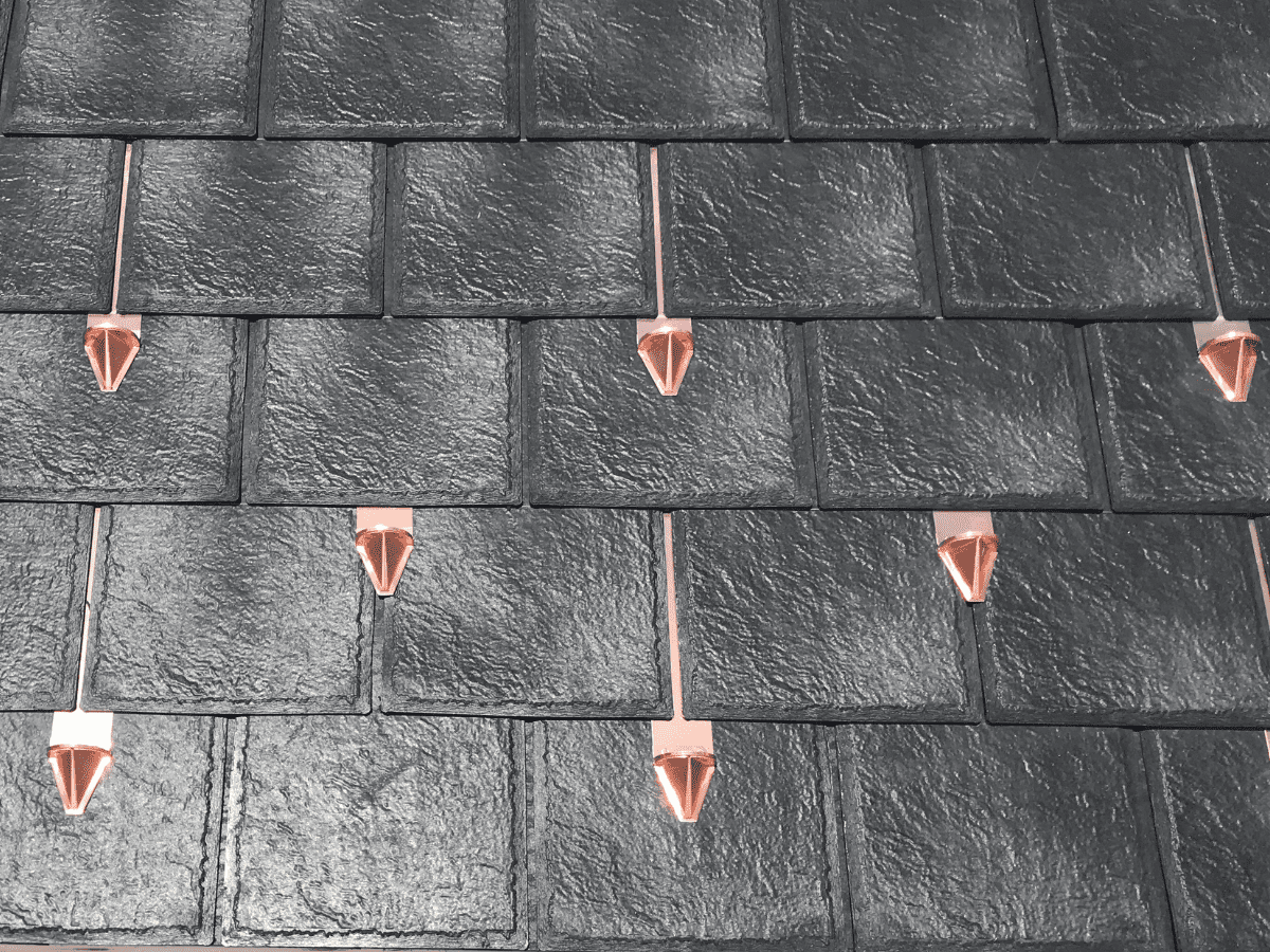 Closeup swatch of the Enviroslate Onyx Black synthetic roof with copper snow guards.