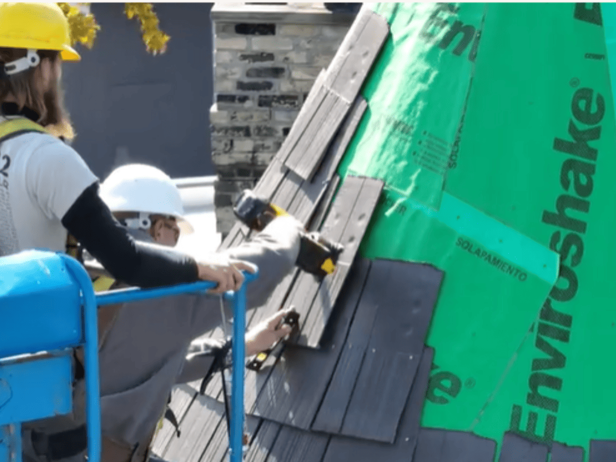 Closeup of roofing contractors on a lift installing Enviroshake to a roof turret with the Enviroshield synthetic peel and stick underlayment still visible
