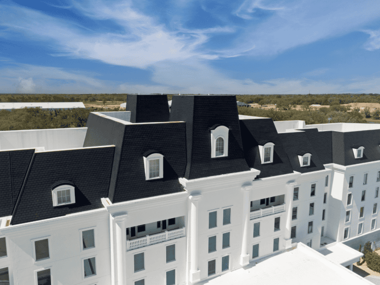 Luxury hotel with an Onyx Black Enviroslate roof and white exterior under a bright blue sky.