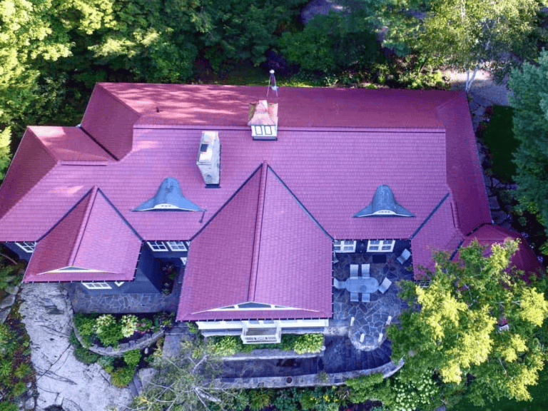 Aerial view of home with vibrant Ruby Red Enviroshake roof surrounded by lush green trees.