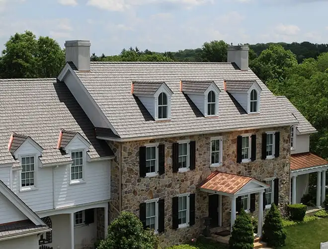 Stone residential home with an Enviroshake aged cedar synthetic roof and copper accents, showing an authentic cedar shake look.