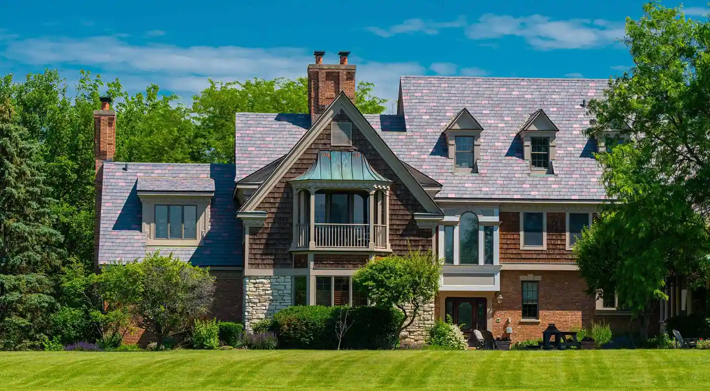 Lakeside home with multitone Enviroslate roof, wood and stone accents, and manicured green lawn.