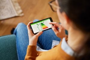 woman check house efficiency rating of her apartment on smartphone. Looking at energy saving capacity of house on mobile screen.